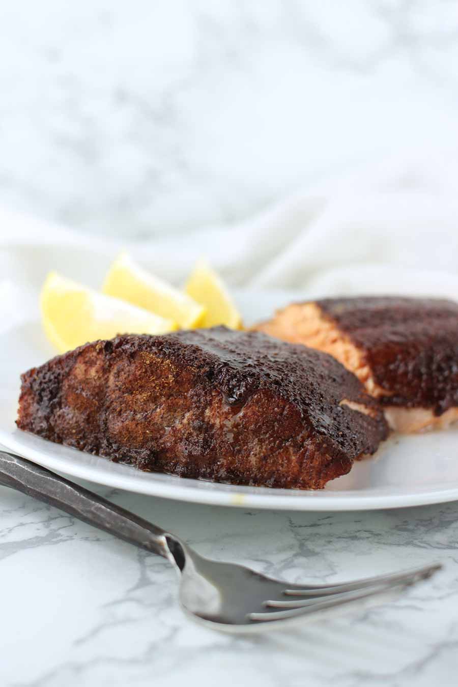 Maple-Glazed Salmon filets on a plate with lemon slices for garnish from acleanplate.com